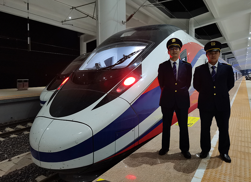 劉銀能（右一）與中國師父鄔俊鴻在動車組前合影。受訪者供圖